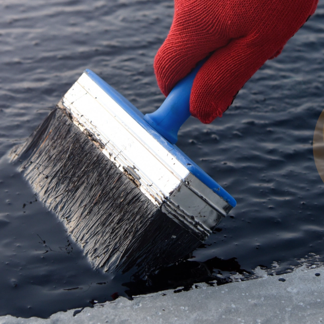 black waterproof solution being applied with a blue brush